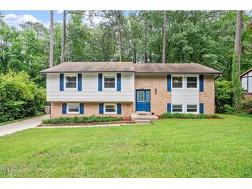 Charming split-level home featuring a brick facade, well-manicured lawn, and mature trees at 1109 Buckingham Rd, Garner, NC 27529