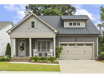 Charming home with a covered front porch, two rocking chairs, and attractive landscaping at 1374 Patriot Points Way, Fuquay Varina, NC 27526