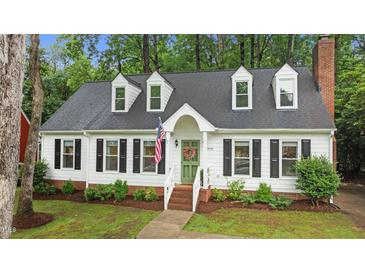 Charming home featuring a green door with a wreath, black shutters and well manicured landscaping at 3016 Bolo Trl, Raleigh, NC 27615
