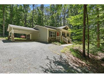 Charming home with a covered carport and welcoming red front door nestled in a lush, wooded setting at 305 Old School Rd, Chapel Hill, NC 27516