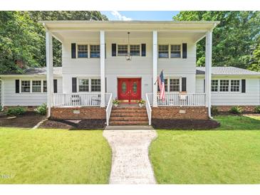 Charming two-story home featuring a white exterior, front porch, red door and well-maintained lawn at 307 Country Club Dr, Durham, NC 27712