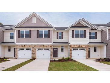 Charming townhome exterior with stone accents, attached garages, and manicured lawn at 3922 Well Fleet Dr, Fuquay Varina, NC 27526