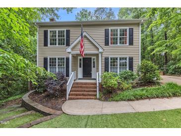 Charming two-story home with wood siding, black shutters, manicured lawn, and an American flag at 5805 Bayberry Ln, Raleigh, NC 27612