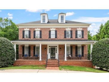 Beautiful brick home featuring dormer windows, black shutters, and a welcoming covered front porch at 6217 Battleford Dr, Raleigh, NC 27612
