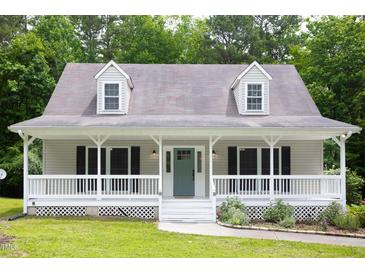 Charming exterior view of home featuring a spacious porch and lovely landscaped yard at 657 Lakeview Dr, Stem, NC 27581