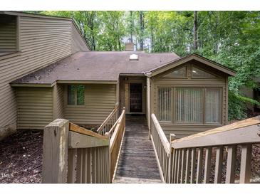 View of a quaint home exterior with a wooden walkway leading up to the front door and lush surrounding greenery at 73 Stoneridge Rd, Durham, NC 27705