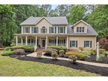 Inviting two-story home with a charming front porch and manicured landscaping at 7811 Still Crossing Rd, Chapel Hill, NC 27516