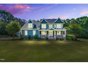 Stunning two-story blue house with a welcoming front porch and beautifully manicured lawn at 227 Paraggi Ct, Clayton, NC 27527