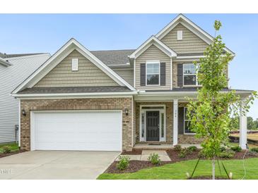 Charming two-story home featuring brick accents, attached two-car garage, and a well-manicured front lawn at 304 Ford Meadows Dr, Garner, NC 27529