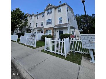 A cream-colored townhouse complex featuring a white picket fence and well-maintained landscaping at 401 Coalinga Ln # 106, Raleigh, NC 27610
