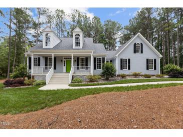 Charming two-story home featuring a welcoming front porch with a bright green door and well-manicured landscaping at 4416 Thistlehill Ct, Raleigh, NC 27616