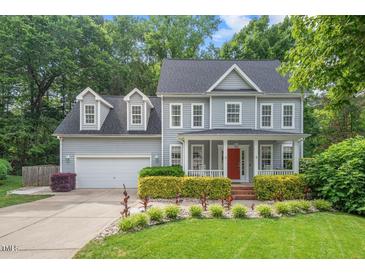 Charming two-story home featuring a manicured lawn, bright red door, and lovely landscaping at 5 Providence Ridge Ln, Durham, NC 27713