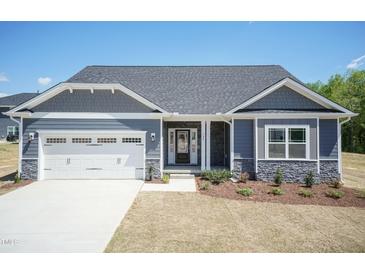 Charming single-story home with a two-car garage, stone accents, and manicured front yard at 56 Braddock Ct, Garner, NC 27529