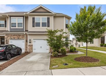Charming townhome featuring a one car garage, neutral siding, and well manicured front yard at 1102 Latitude Dr, Durham, NC 27713