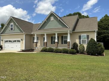 Charming single-story home showcasing a well-manicured lawn, neutral siding, and inviting front porch with stone accents at 119 Hunterwood Pl, Benson, NC 27504