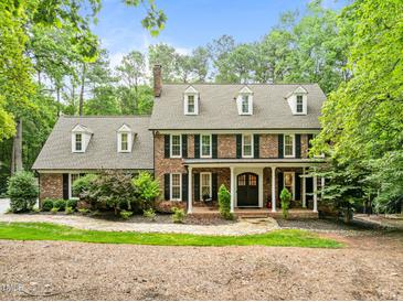 Classic brick home with manicured landscaping, dormer windows and covered front porch offers timeless curb appeal at 1501 Chatsworth Ln, Raleigh, NC 27614