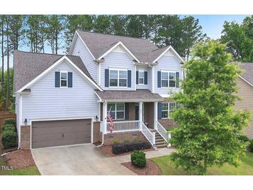 Charming two-story home with blue siding, a covered porch, and a well-manicured front yard at 208 Cecelia Ct, Cary, NC 27519