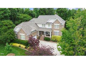 Beautiful two-story brick home with mature trees, lush landscaping, and a welcoming front porch at 220 Cole Valley Dr, Cary, NC 27513