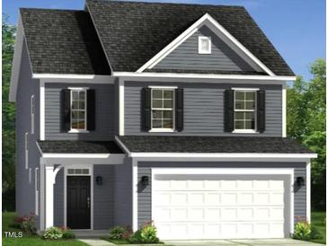 Two-story home boasts a welcoming facade, a two-car garage, classic shutters, and manicured landscaping at 221 Steel Springs Ln # 23, Angier, NC 27501