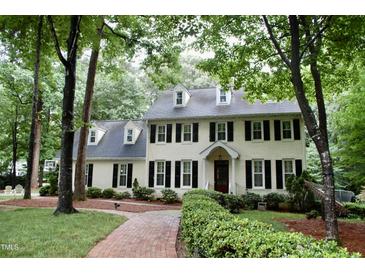 Stately two-story home featuring dormer windows, black shutters, manicured landscaping, and a brick pathway at 2216 Countrywood North Rd, Raleigh, NC 27615