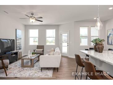 Bright living room with hardwood floors, a ceiling fan, and lots of natural light from multiple windows at 3916 Well Fleet Dr, Fuquay Varina, NC 27526