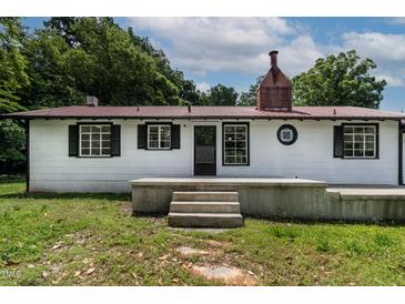 Charming white home featuring black shutters and a red metal roof, providing a modern touch to the classic design at 519 W Raleigh St, Siler City, NC 27344