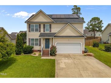 Charming two-story home featuring solar panels, a well-maintained lawn, and a two-car garage at 76 Haywood St, Spring Lake, NC 28390