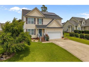 Charming two-story home featuring solar panels, a two-car garage, and a well-manicured front lawn at 76 Haywood St, Spring Lake, NC 28390