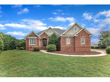 Charming brick home with landscaped yard and inviting front entrance with a blue sky backdrop at 7800 Twin Pines Way, Fuquay Varina, NC 27526