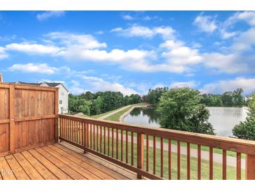 Relaxing back deck view of a serene lake and paved walking trail on a partly cloudy day at 816 Lilyquist Way, Wake Forest, NC 27587