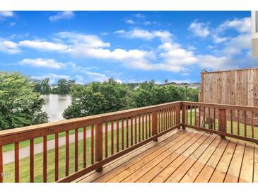 Spacious wooden back deck overlooking a serene lake and lush green walking trail at 816 Lilyquist Way, Wake Forest, NC 27587
