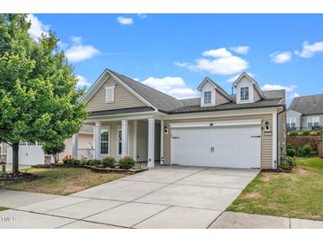 Charming home featuring a two-car garage, beige siding, manicured lawn, and well-maintained landscaping at 826 Downfield Ln, Fuquay Varina, NC 27526