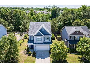 Charming two-story home with a manicured lawn, beautiful trees, and an attached two-car garage at 1004 Bridlemine Dr, Fuquay Varina, NC 27526