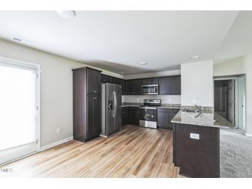 Modern kitchen featuring stainless steel appliances and dark cabinetry with granite countertops at 103 Hampshire Pl, Kenly, NC 27542