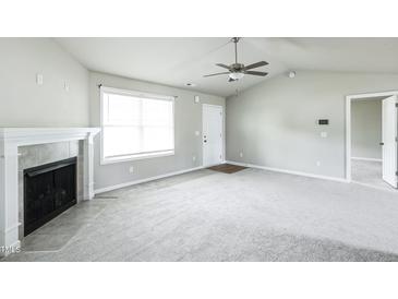 Bright living room features a fireplace, large window, and ceiling fan at 103 Hampshire Pl, Kenly, NC 27542