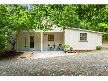 Charming home exterior with covered porch, gravel driveway, and lush landscaping at 1085 Bynum Rd, Pittsboro, NC 27312
