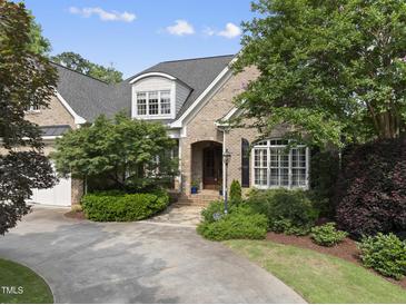 Charming brick home featuring an arched entryway, lush landscaping, and a spacious driveway with a side entry garage at 1210 Brooks Ave, Raleigh, NC 27607