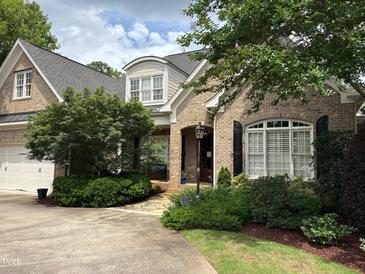 Charming brick home features a well-manicured lawn, mature trees, and a welcoming front porch at 1210 Brooks Ave, Raleigh, NC 27607