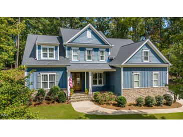 Charming two-story home with blue siding, stone accents, landscaped yard and American flag at 147 Gentry Dr, Pittsboro, NC 27312