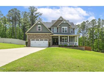 Charming two-story home featuring a stone facade, a two-car garage, and a welcoming front porch at 187 Farrah-Shea Way, Angier, NC 27501