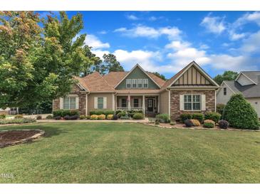 Charming home with a manicured lawn, stone accents, and inviting front porch at 212 Fieldtrial Cir, Garner, NC 27529