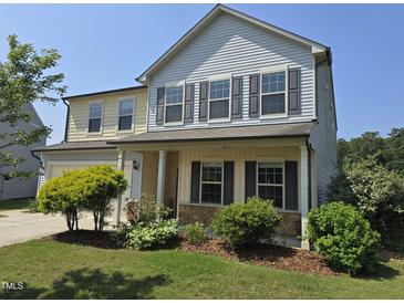 Charming two-story home featuring stone accents, a covered porch, and a well-manicured lawn at 2511 Dalmahoy Ln, Fuquay Varina, NC 27526