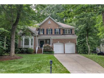 Traditional two-story brick home featuring a manicured lawn, attached two-car garage, and mature trees at 522 N Scotswood Blvd, Hillsborough, NC 27278