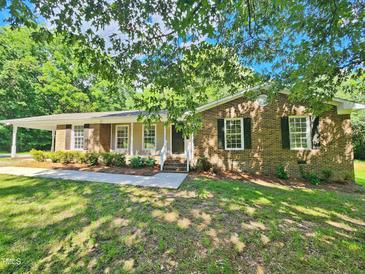 Charming brick home featuring a covered porch and lush green lawn at 5614 Skyline Dr, Durham, NC 27712