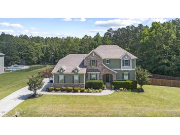 Beautiful two-story home with a stone and green facade and mature landscaping at 6521 Sunset Manor Dr, Wake Forest, NC 27587