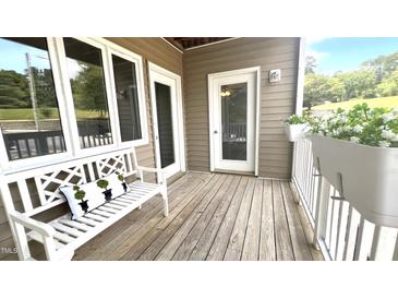 Inviting porch with white bench, decorative pillow, potted plants, and wooden floorboards at 923 Springfork Dr, Cary, NC 27513