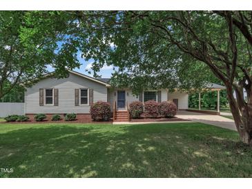 Charming single-story home with a well-maintained lawn, mature trees, and a convenient covered carport at 105 Poplar Dr. Dr, Clayton, NC 27520