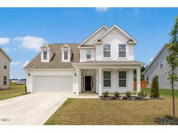 Charming two-story home boasts a manicured lawn, attached garage, and inviting front porch at 116 Hayfield Dr, Lillington, NC 27546