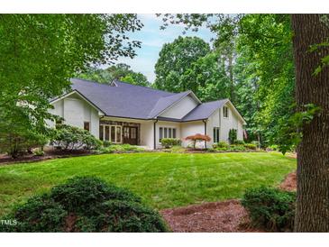 Charming brick home with a manicured lawn and lush landscaping in a serene, wooded setting at 1301 King Cross Ct, Raleigh, NC 27614