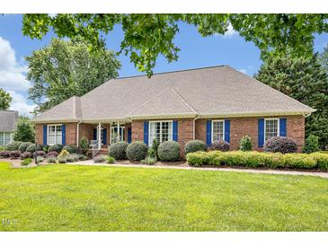 Beautiful single-story brick home with blue shutters, manicured landscaping, and lush green lawn at 14 Marigold Pl, Durham, NC 27705
